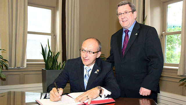 Régis Labeaume, maire de la ville de Québec, invite Yvon Vallières, ministre responsable des Affaires intergouvernementales canadiennes et de la Francophonie canadienne, à signer le Livre d'or de la ville du Québec.